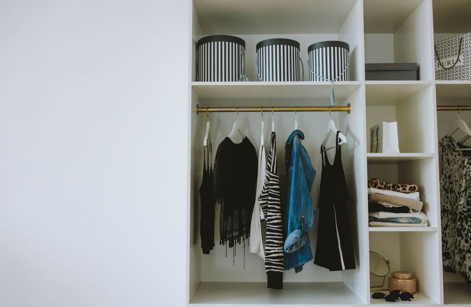 Open wardrobe with neatly arranged everyday clothing and open shelf space.