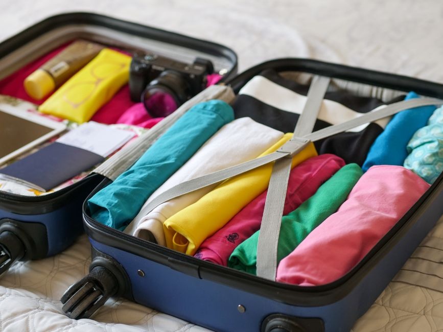 Open suitcase neatly packed with colorful clothing for a short trip.