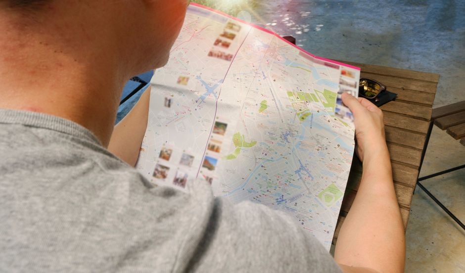 Traveler reading a folded city map while walking outdoors.
